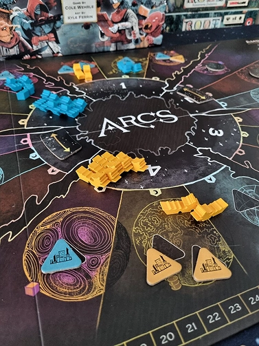 az ARCS társasjáték játékmenete látható egy asztalon, különböző színű űrhajó figurákkal, jelölőkkel és stratégiai játéktáblával, sci-fi témájú társasjáték közeli fotója játék közben